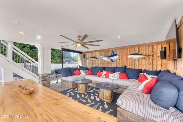 living room with wooden walls, stairs, decorative columns, recessed lighting, and a ceiling fan