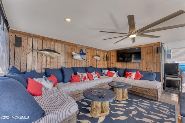 living area featuring wood walls and a ceiling fan