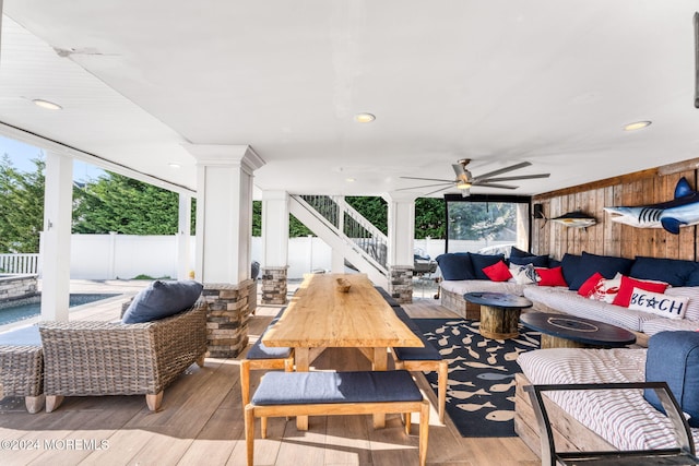 view of patio with a deck, a ceiling fan, an outdoor living space, fence, and stairs