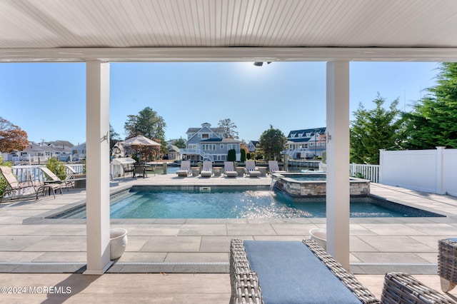 view of pool featuring a residential view, fence, a pool with connected hot tub, and a patio area