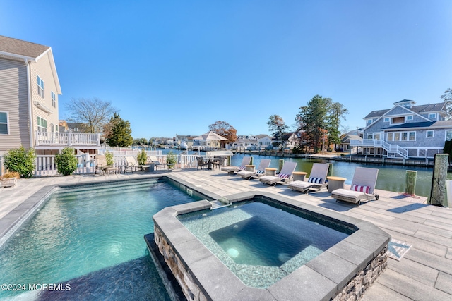 view of pool with a pool with connected hot tub, a water view, a residential view, a dock, and a patio area