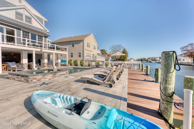 exterior space with an in ground hot tub, an outdoor pool, a water view, and a patio