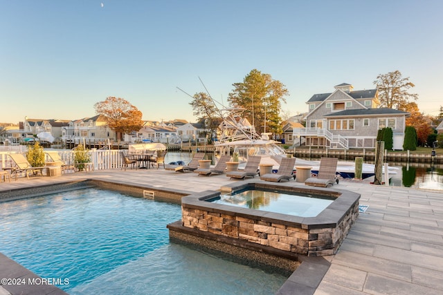 view of pool featuring a residential view, a pool with connected hot tub, and a patio