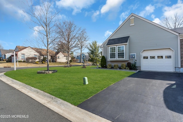 view of side of property featuring aphalt driveway, a lawn, and a garage