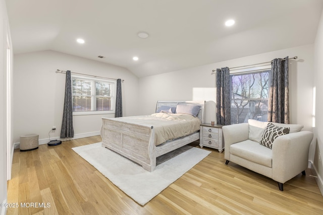 bedroom with multiple windows, baseboards, lofted ceiling, and light wood-style floors