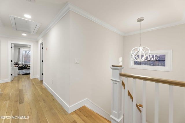 hall featuring baseboards, attic access, ornamental molding, an upstairs landing, and light wood-style floors