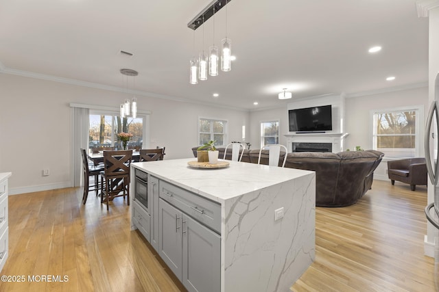 kitchen featuring light wood-style floors, gray cabinets, a fireplace, and crown molding