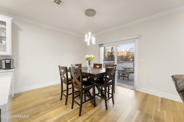 dining room featuring baseboards, visible vents, an inviting chandelier, light wood-style flooring, and ornamental molding
