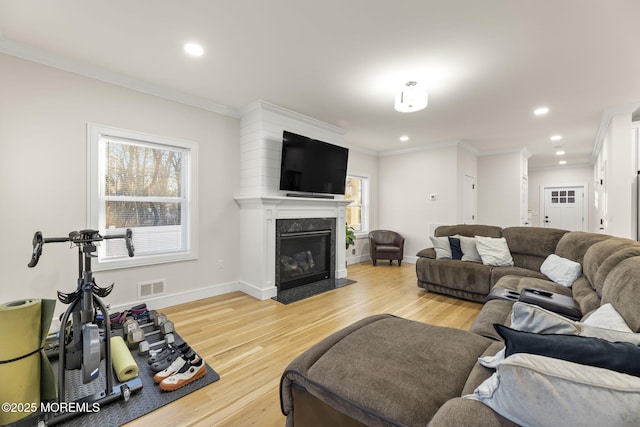 living room with a premium fireplace, plenty of natural light, visible vents, and light wood finished floors