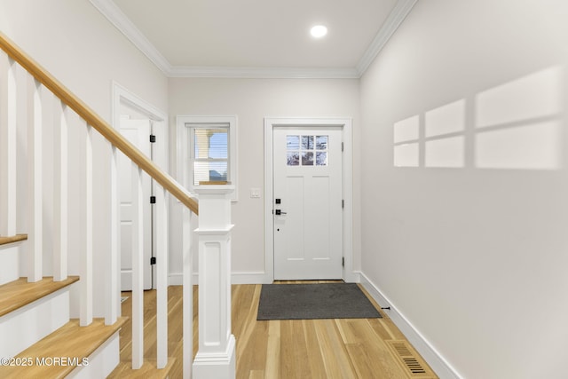 entrance foyer with visible vents, light wood-style flooring, and ornamental molding