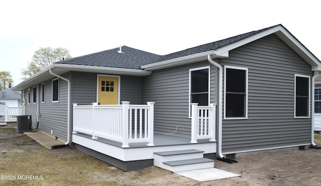 rear view of property featuring a shingled roof and cooling unit