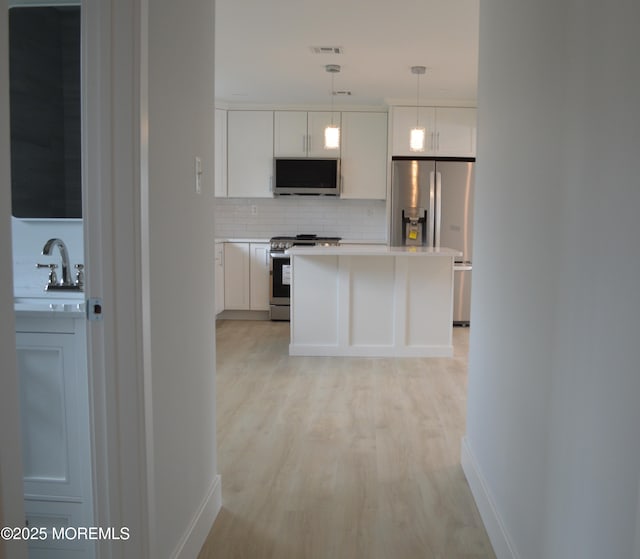 71 Montserrat St, Toms River, NJ 08757 - kitchen with stainless steel appliances, light wood-type flooring, decorative backsplash, a sink, and light countertops