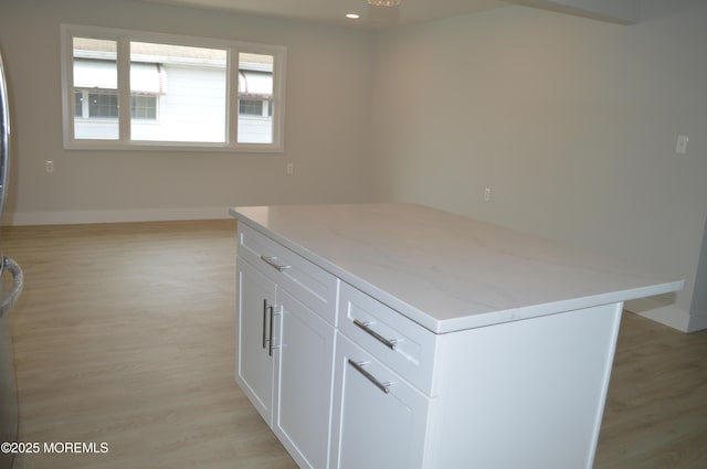 71 Montserrat St, Toms River, NJ 08757 - kitchen with a kitchen island, light wood-style floors, light stone counters, white cabinets, and baseboards