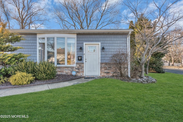 entrance to property with a lawn and stone siding