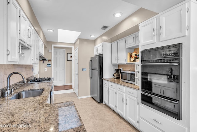 kitchen with tasteful backsplash, under cabinet range hood, appliances with stainless steel finishes, white cabinetry, and a sink