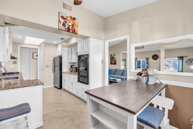 kitchen featuring visible vents, appliances with stainless steel finishes, white cabinetry, and a warming drawer