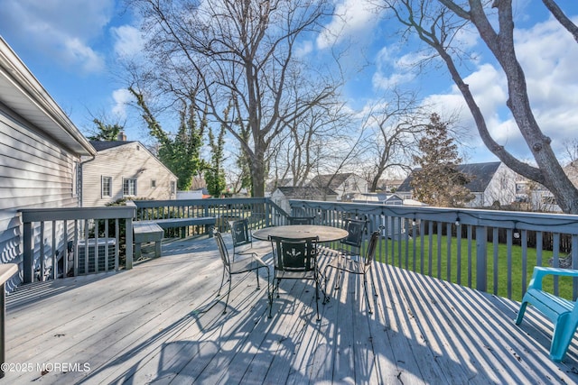 deck with outdoor dining area and a lawn