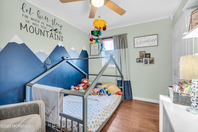 bedroom featuring ceiling fan, baseboards, wood finished floors, and crown molding