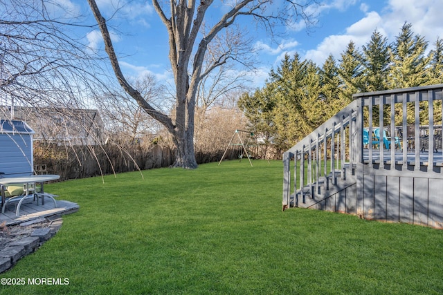 view of yard featuring a playground, a deck, and fence