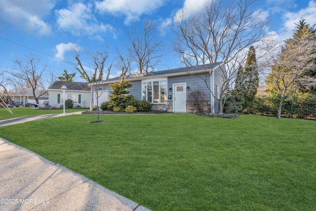 view of front facade featuring a front yard, stone siding, and driveway