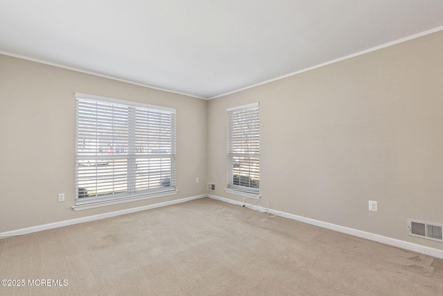 unfurnished room featuring crown molding, light colored carpet, visible vents, and baseboards