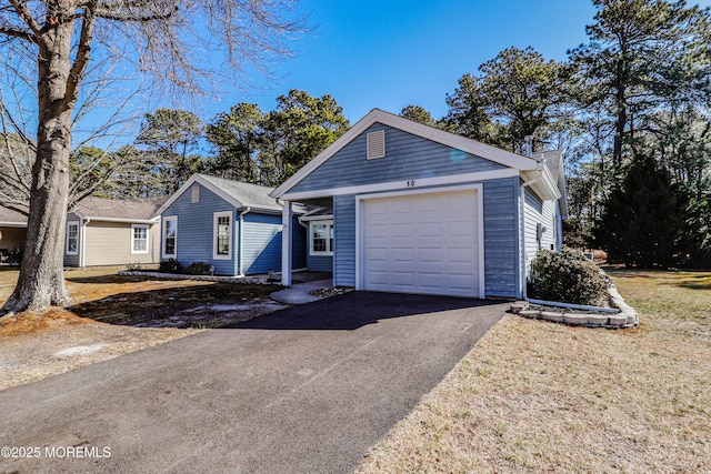 single story home with a garage, a chimney, and aphalt driveway