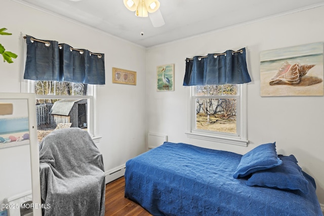 bedroom featuring multiple windows, wood finished floors, ornamental molding, and a baseboard radiator