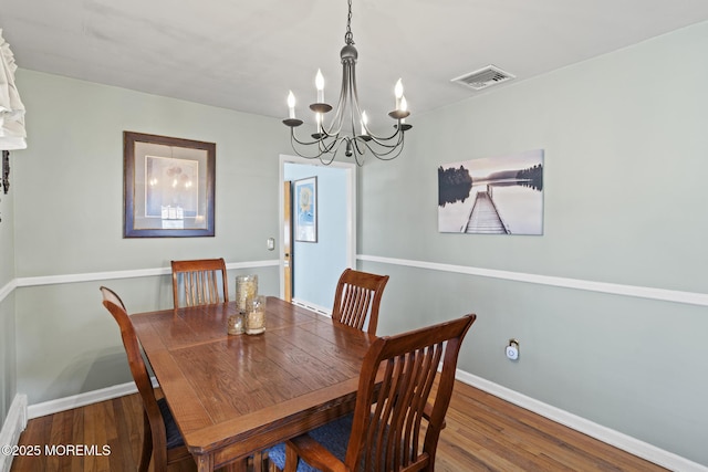 dining space featuring a chandelier, visible vents, baseboards, and wood finished floors