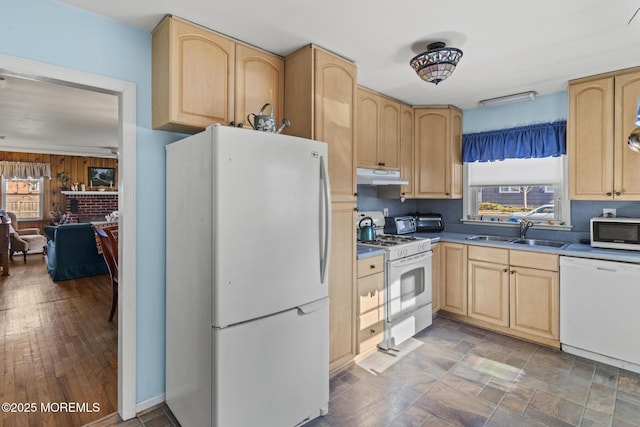 kitchen with a sink, white appliances, under cabinet range hood, and light brown cabinets