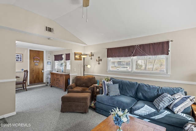 living area with light carpet, visible vents, plenty of natural light, and vaulted ceiling