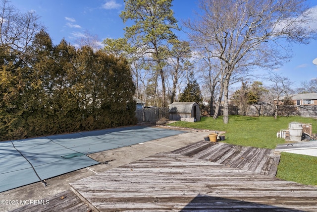 deck with an outbuilding, fence, a yard, a storage shed, and a fenced in pool