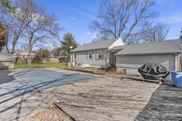 rear view of property with entry steps, fence, and roof with shingles