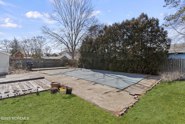 view of swimming pool featuring a deck, a fenced backyard, and a lawn