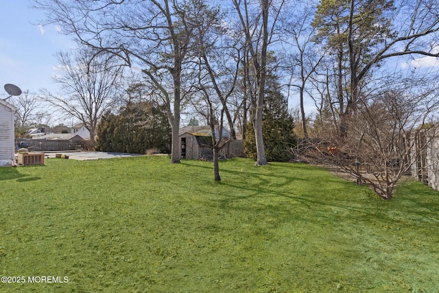 view of yard with a storage shed, central AC, fence, and an outdoor structure