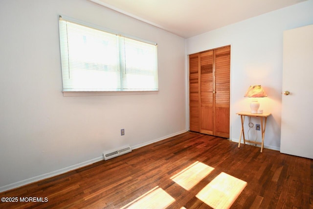 unfurnished bedroom with wood finished floors, visible vents, a closet, and baseboards