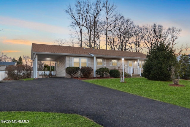 single story home with an attached carport, a front lawn, and aphalt driveway