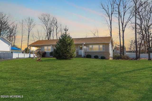 front of property at dusk with a yard and fence