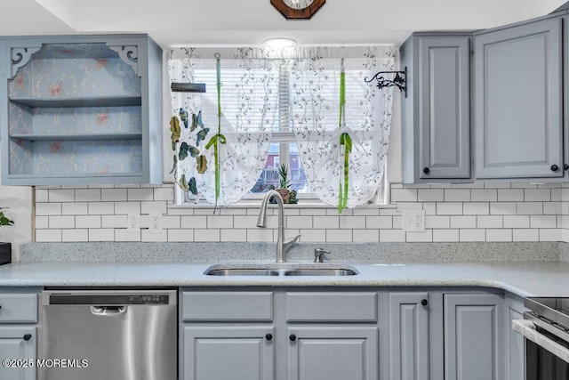 kitchen with gray cabinets, a sink, light countertops, stainless steel dishwasher, and backsplash