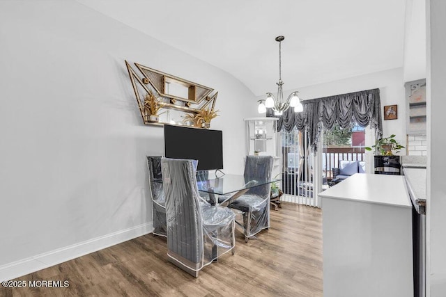 dining space with a notable chandelier, baseboards, lofted ceiling, and wood finished floors