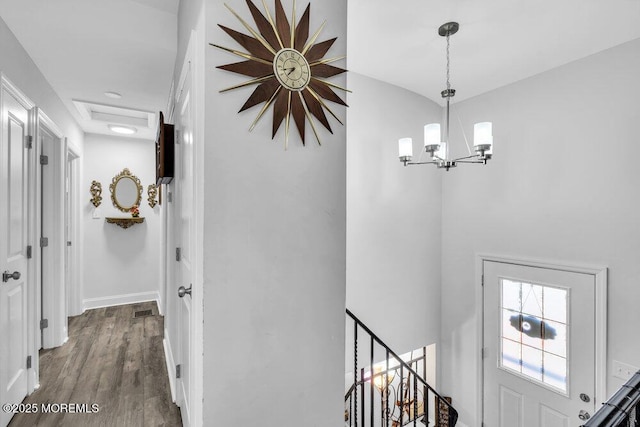 hallway with a notable chandelier, an upstairs landing, wood finished floors, and baseboards