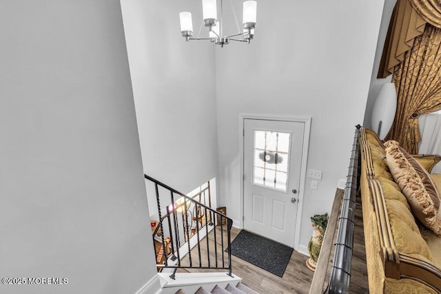 foyer featuring a chandelier, stairway, baseboards, and wood finished floors