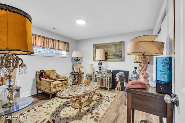 sitting room with visible vents, baseboards, and wood finished floors