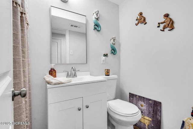 bathroom featuring visible vents, toilet, and vanity