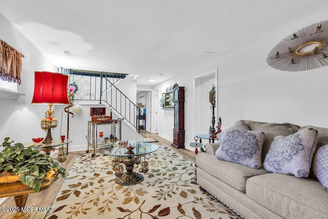 living room with stairs, wood finished floors, visible vents, and baseboards