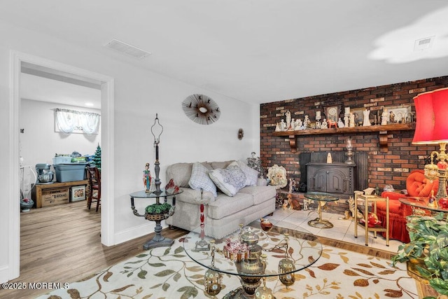 living room featuring visible vents, baseboards, wood finished floors, and a wood stove