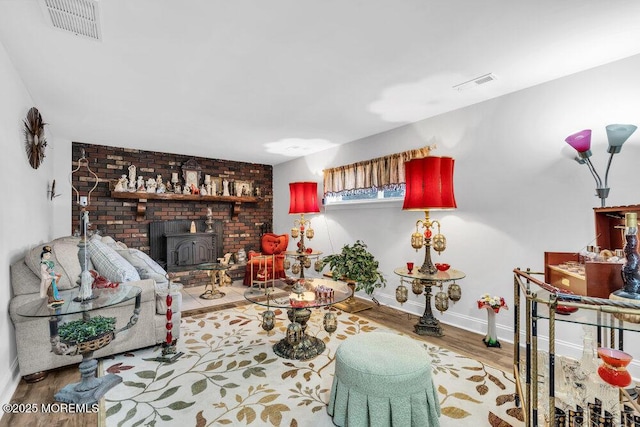 living room with visible vents, a wood stove, baseboards, and wood finished floors