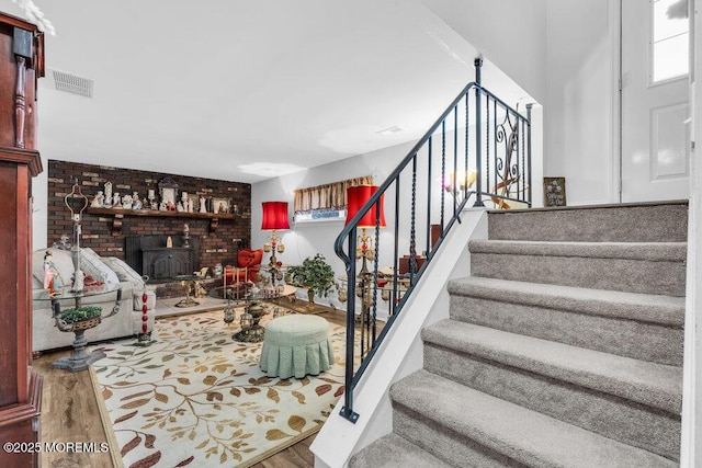 staircase with visible vents, a wood stove, and wood finished floors