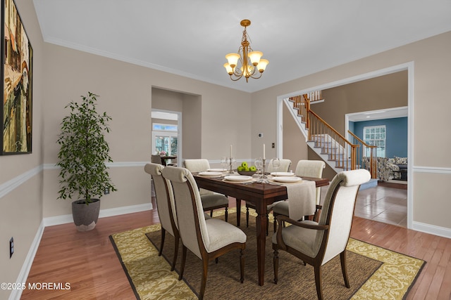 dining space featuring a chandelier, baseboards, wood finished floors, and crown molding