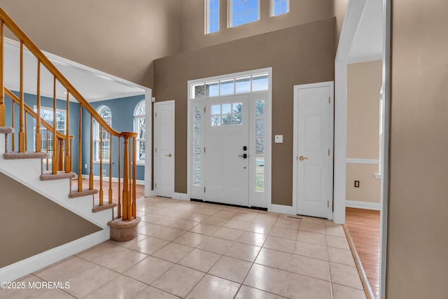 foyer entrance with tile patterned floors, baseboards, plenty of natural light, and stairs