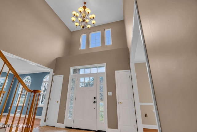 entryway with stairs, a high ceiling, baseboards, and a chandelier